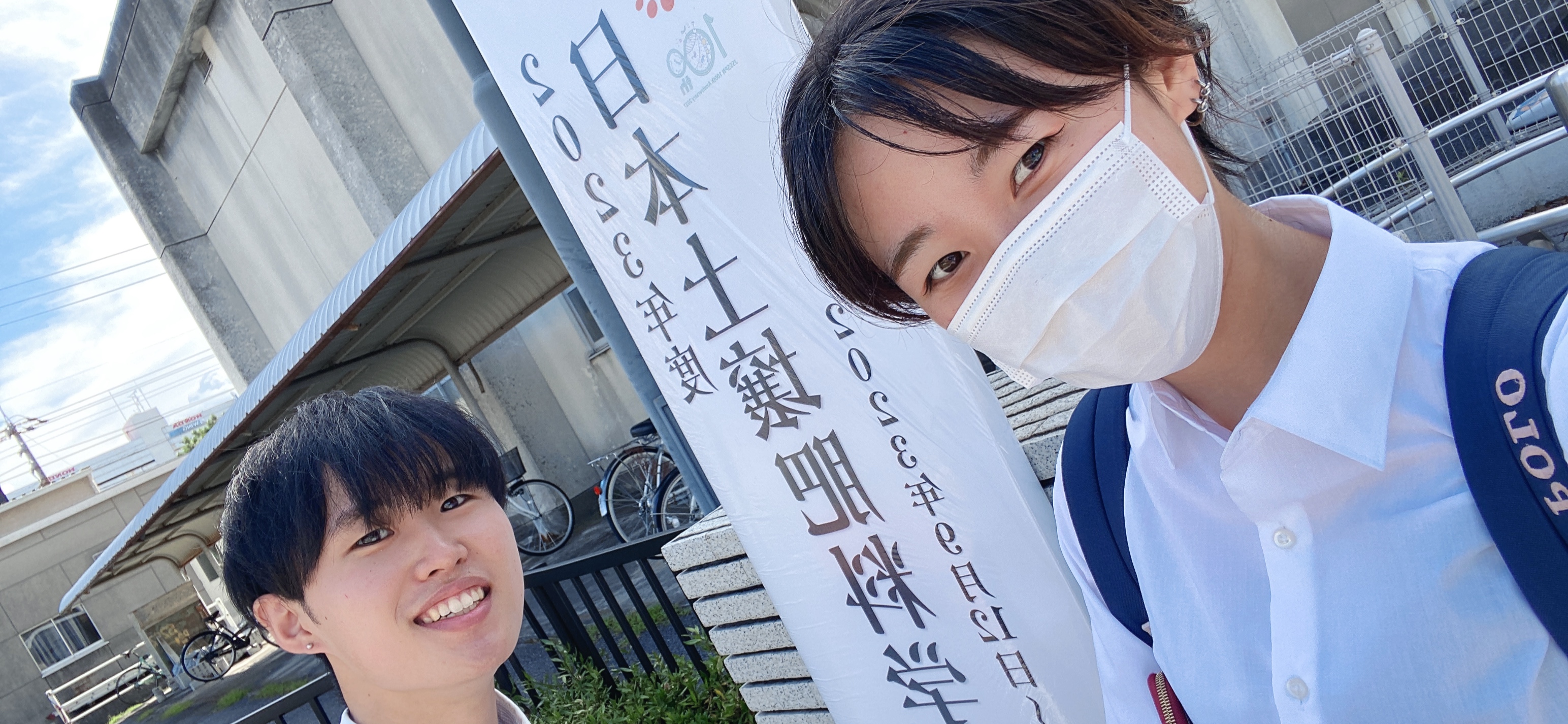 2 students in front of a signboard