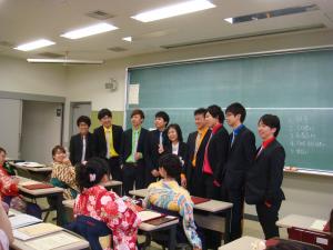 カラーシャツでドレスアップした男子学生に囲まれる学科長