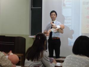 赤ちゃん人形を使用しながら実技の説明を行う島谷康司准教授の様子
